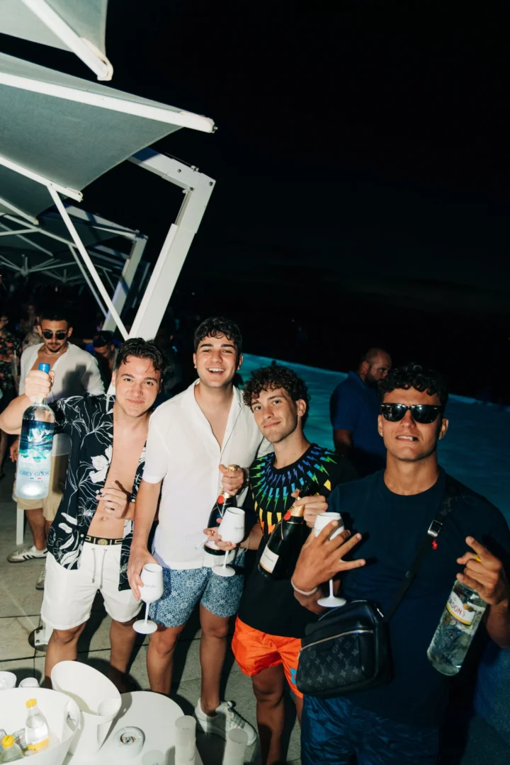 Lads flashing bottles and white wine cups at Cafe Del Mar Malta, poolside beats, late drinks and big grins