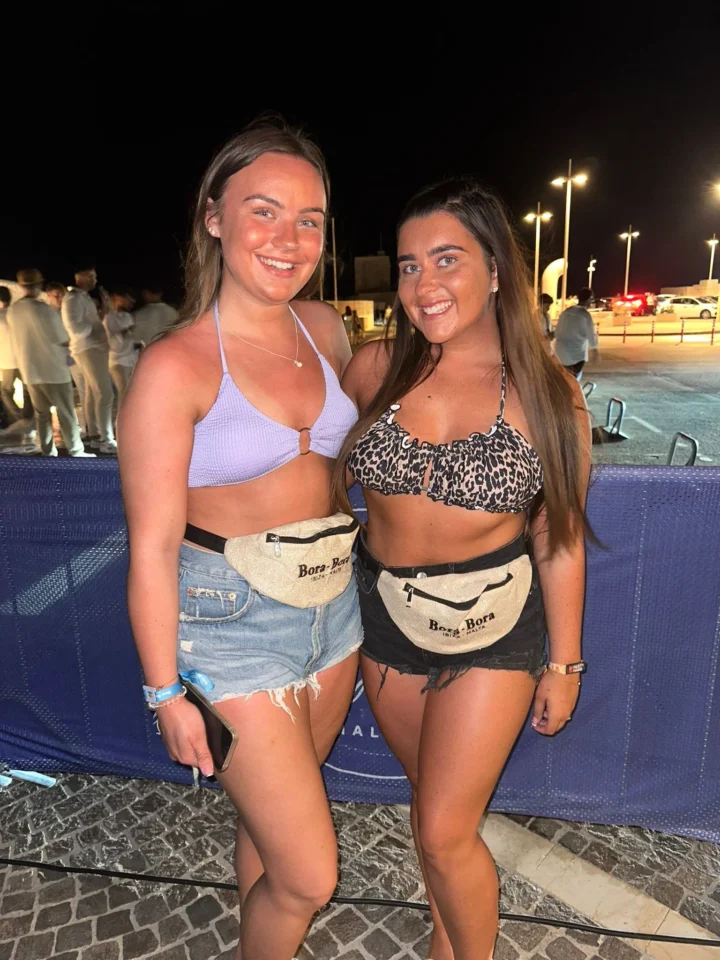Two girls posing at Bora Bora Malta night party with drinks, waist bags, neon lights and busy club crowds