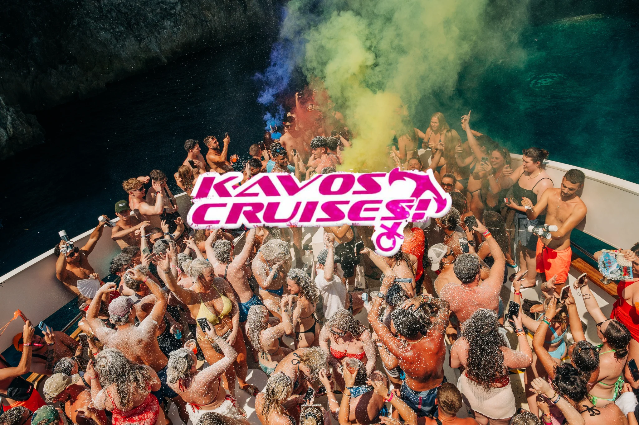 Packed Kavos boat party booze cruise deck covered in foam as the crowd parties under coloured smoke above clear blue water