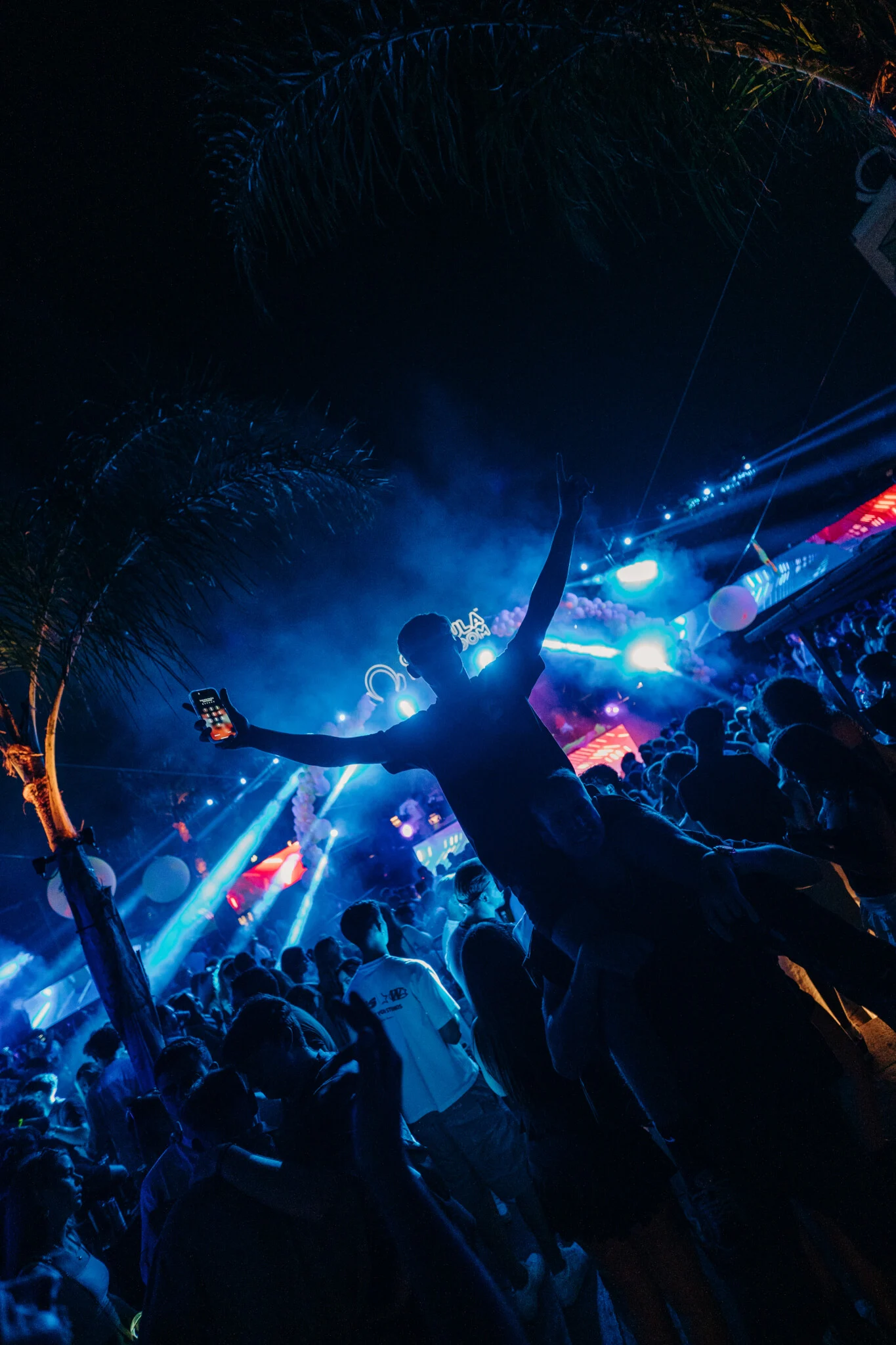 Crowd at Gianpula Club Night in Malta under blue lights, with one lad lifted above the dancefloor holding up his phone.