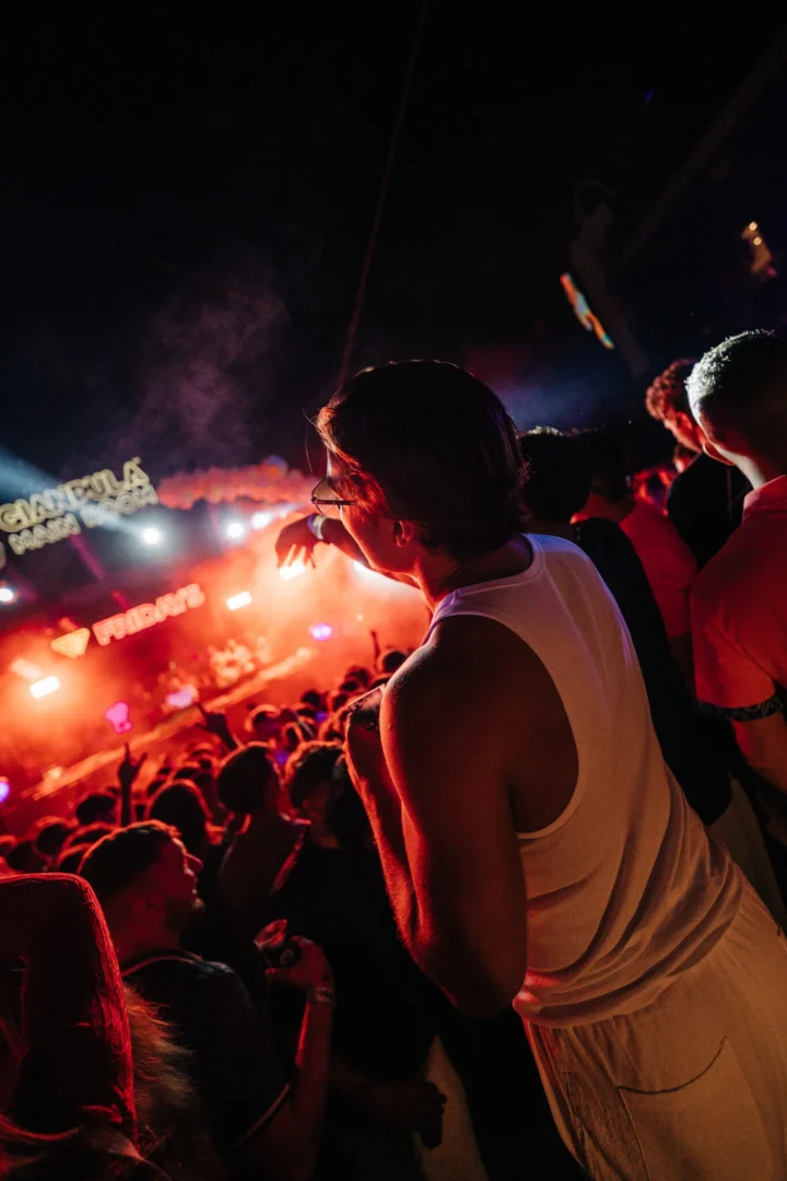 Lad looking over the crowd at Gianpula Club Night in Malta as red lights and smoke fill the stage area below.