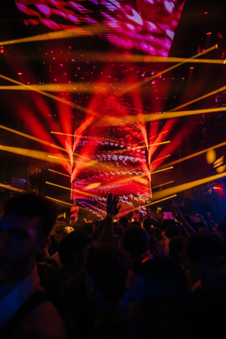 Packed crowd facing the stage under red visuals and sweeping yellow lights at Toy Room Super Club in Malta