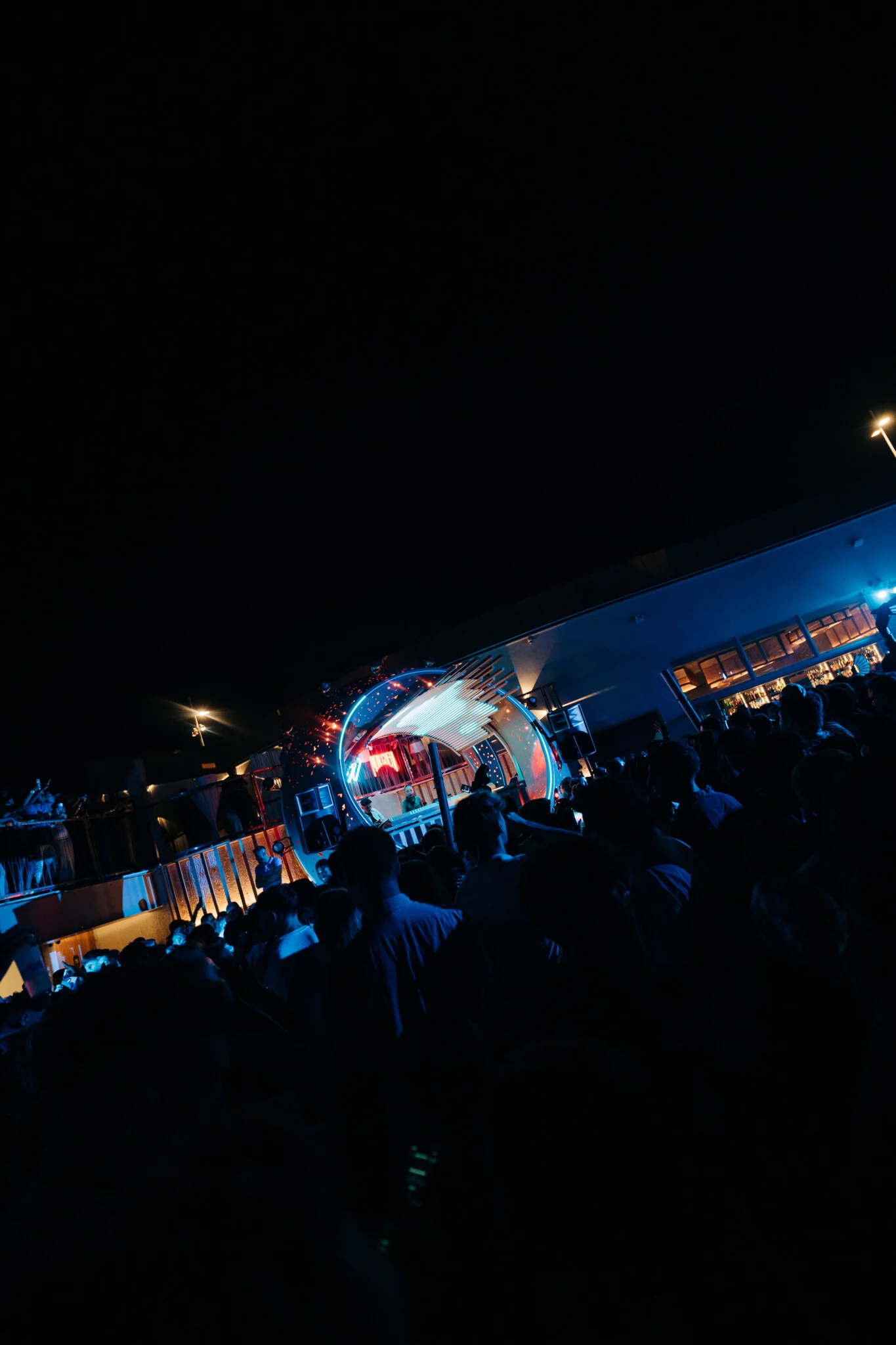 Crowd packed shoulder to shoulder at Cafe Del Mar Malta as neon stage lights fire across the terrace and the DJ booth glows into the night