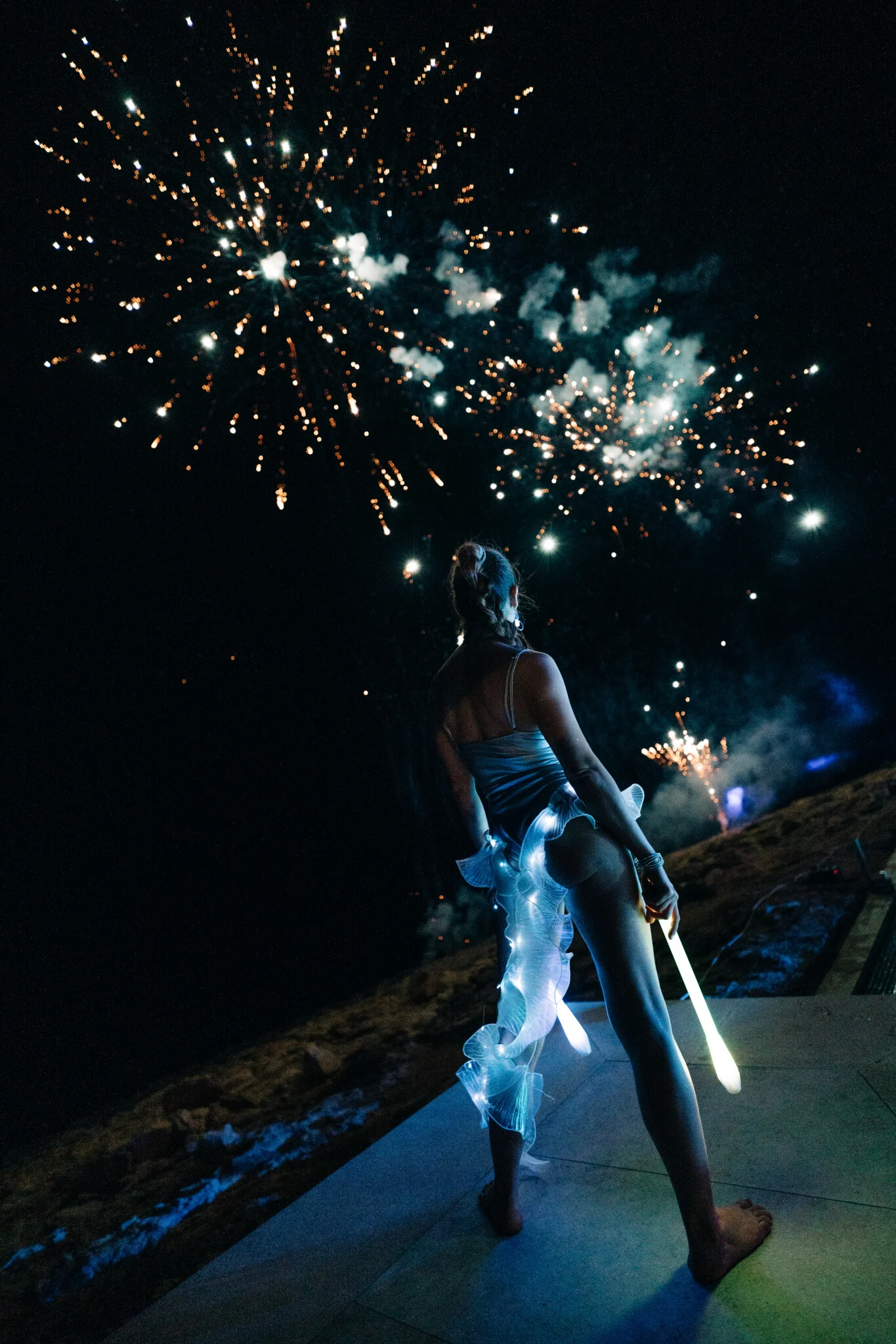Fireworks exploding above Cafe Del Mar Malta as a LED performer lights the terrace with glowing batons and after dark party heat