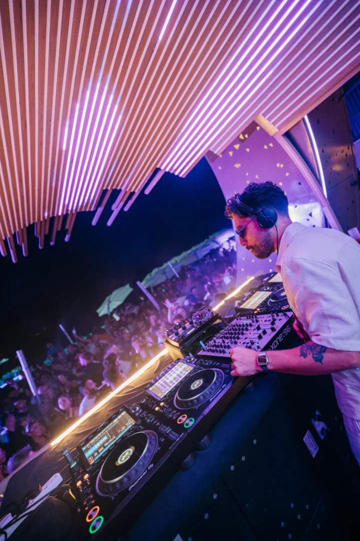 DJ drops peak-time beats at Cafe Del Mar Malta as packed terrace hands go up under pink neon canopy
