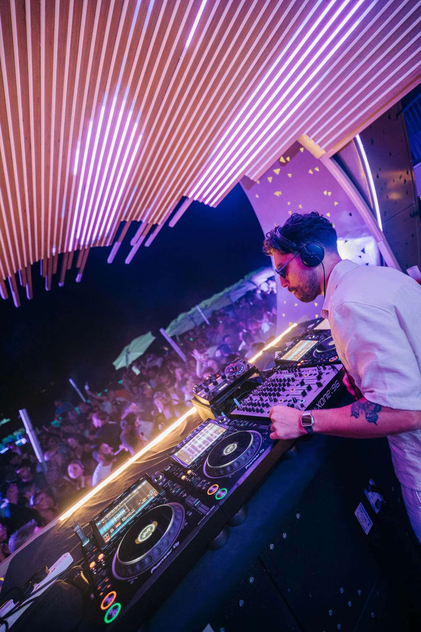 DJ drops peak-time beats at Cafe Del Mar Malta as packed terrace hands go up under pink neon canopy