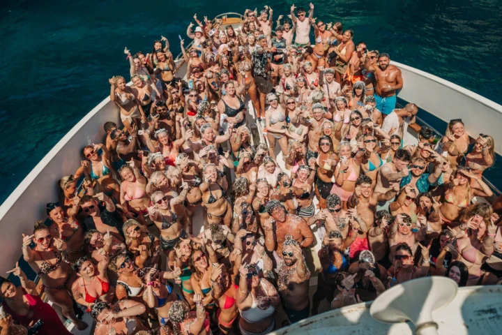 Overhead view of a packed Kavos boat party booze cruise with the crowd posing, cheering and covered in foam on the deck
