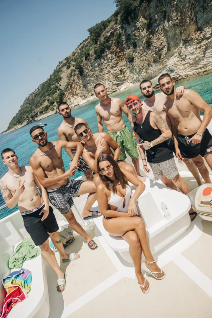 Lads pose with a girl on deck during the Kavos Booze Cruise, turquoise water behind them and drinks close by