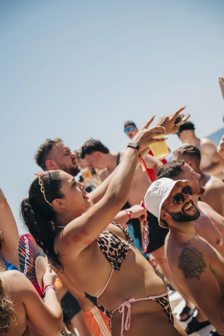 Girls and lads raise drinks and film the madness on the Kavos boat party as the deck party fires up