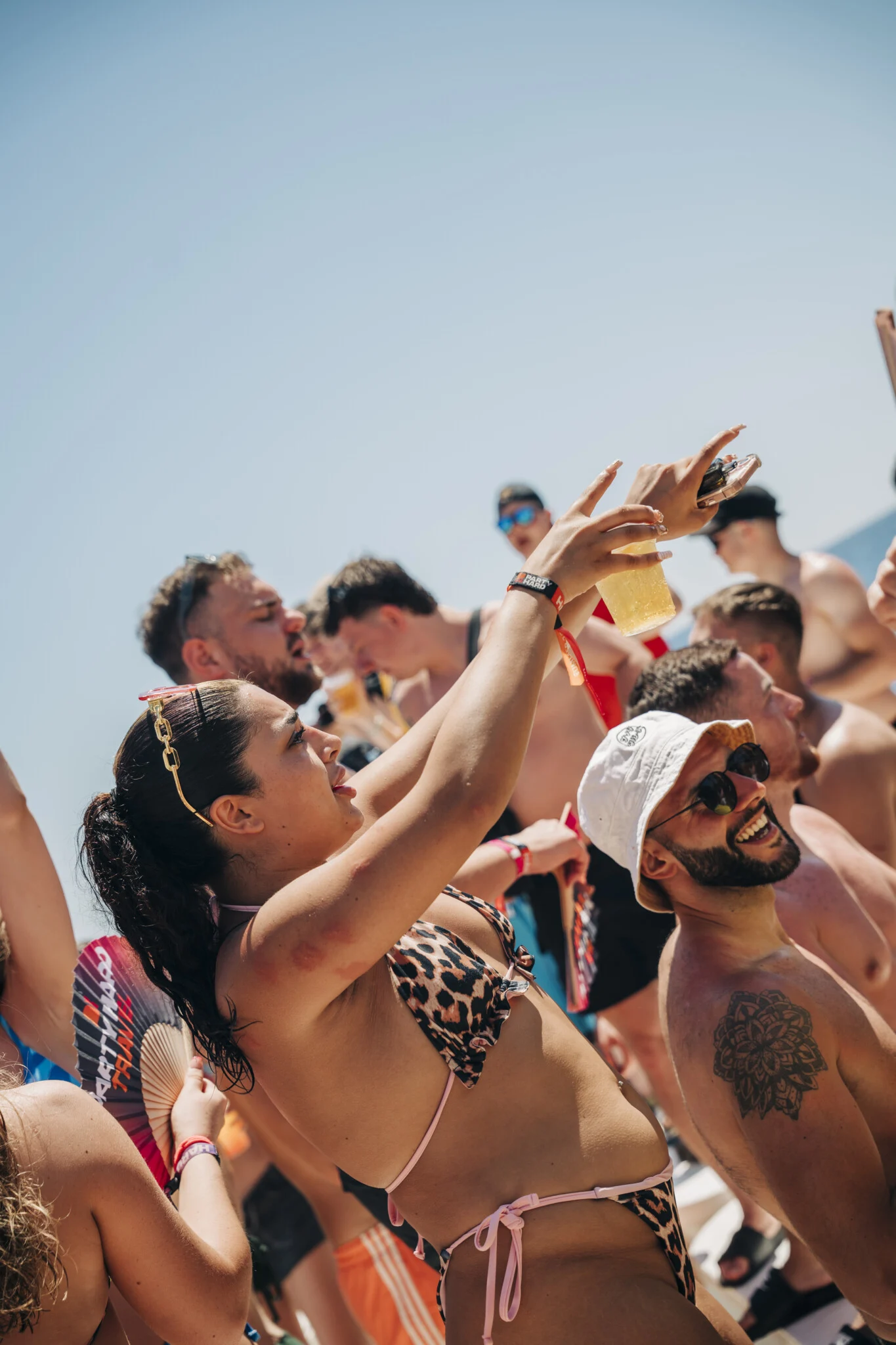 Girls and lads raise drinks and film the madness on the Kavos boat party as the deck party fires up