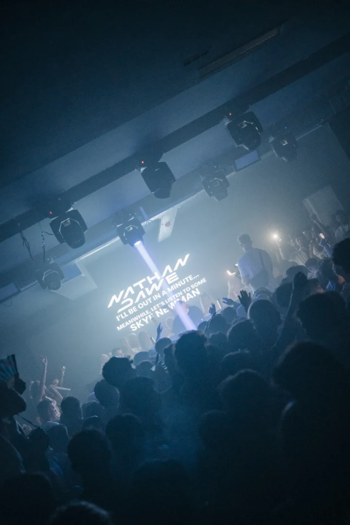 Agenda White Party in Kavos as laser lights cut through smoke, DJ on stage and a packed crowd jumping with hands in the air