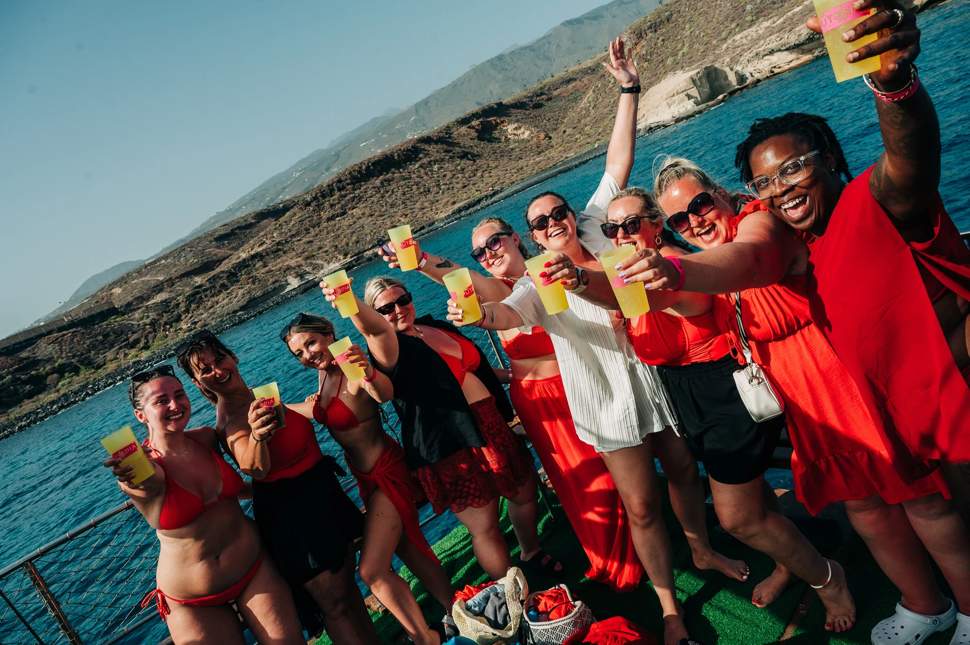 Girls raising drinks on a Tenerife boat party, sunshine out, ocean views and big daytime party energy on deck with the girls lined up