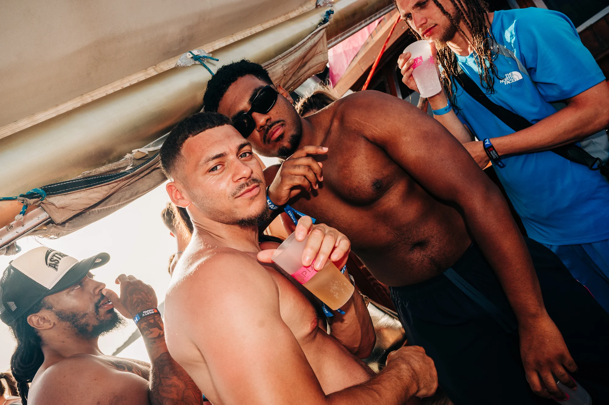 Lads packed onto a Tenerife boat party, drinks in hand, sun out and heavy daytime vibes as the music keeps rolling