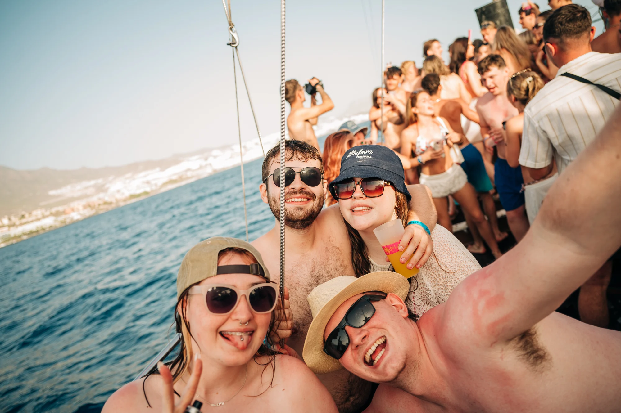 Lads and girls smiling on a Tenerife boat party, drinks raised, sea views behind and nonstop daytime energy