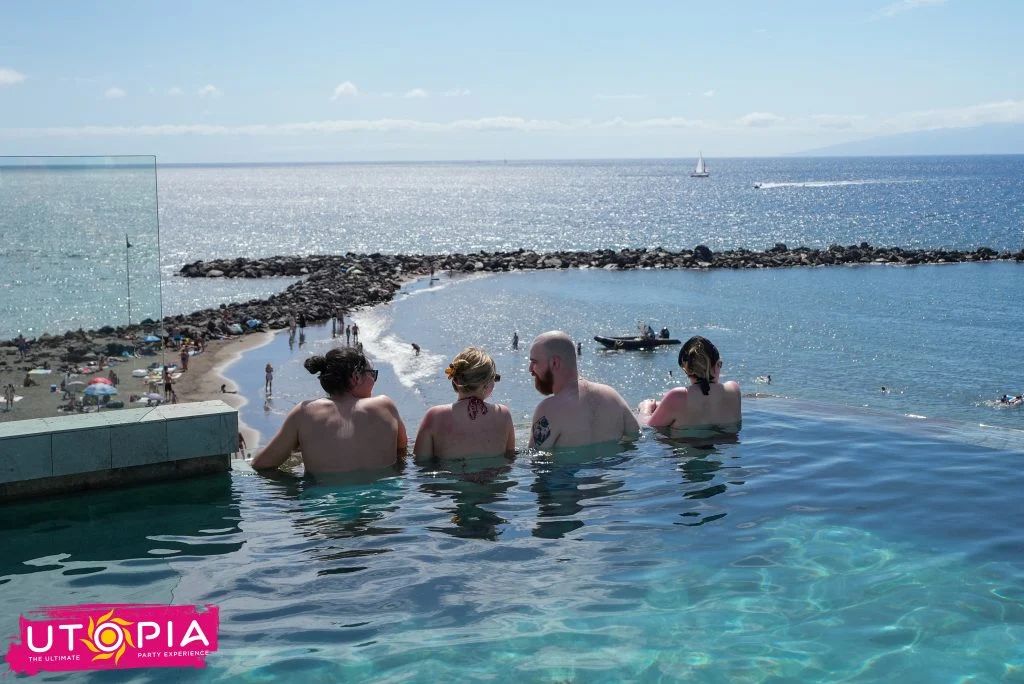 Chilling in the infinity pool at Rooftop Pool Party Tenerife, beers up, sea views, sunshine and daytime party vibes