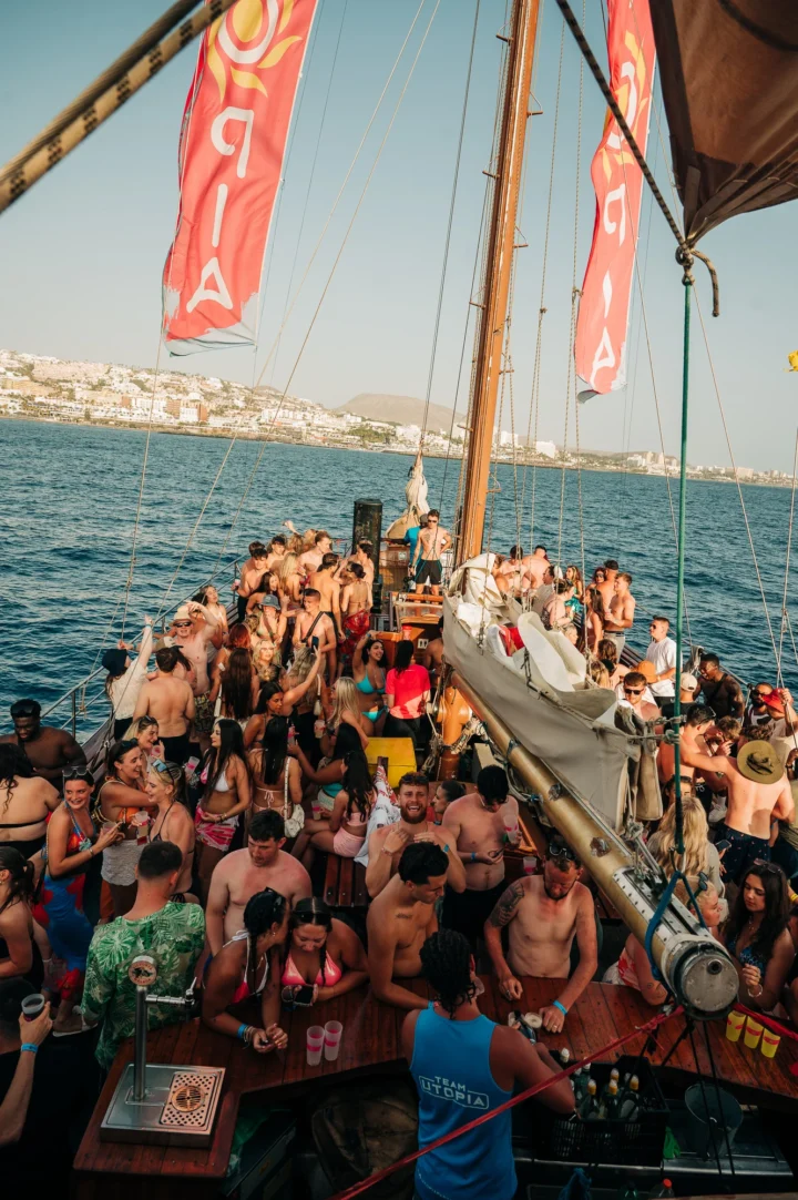 Girls and lads packed on a Tenerife boat party, drinks flowing on deck with DJs, sunshine and full holiday energy