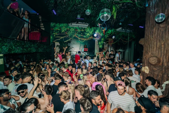 Packed Albufeira club buzzing with partygoers, DJ on the decks, lights flashing and the crowd going wild all night.