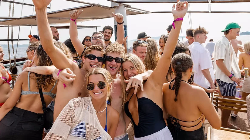 Group of friends posing on the Out to Sea Split booze cruise in Croatia while guests party around them on the boat deck