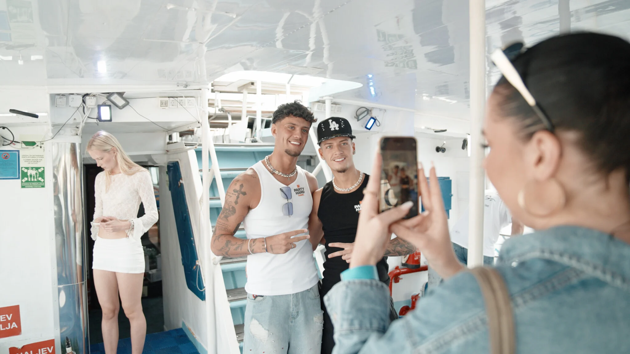 Two lads posing for a photo inside the Split Boat Party in Croatia while a girl takes their picture on board