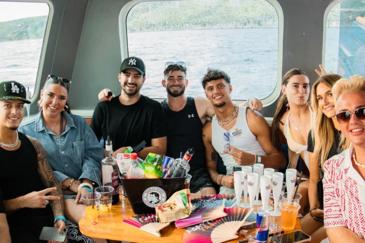 Group of friends sitting together inside the Split booze cruise in Croatia with drinks, bottles and party cups on the table