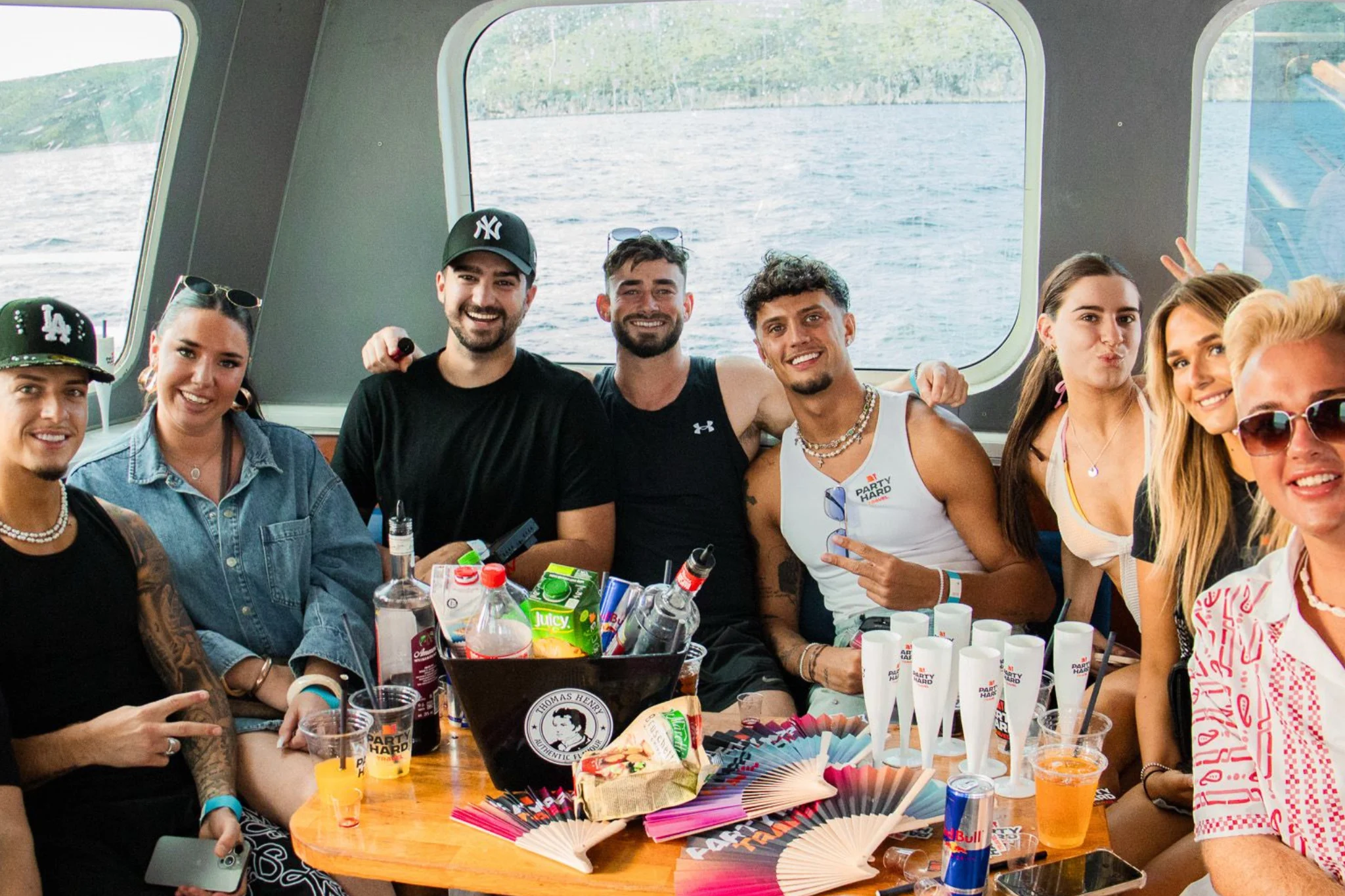 Group of friends sitting together inside the Split booze cruise in Croatia with drinks, bottles and party cups on the table