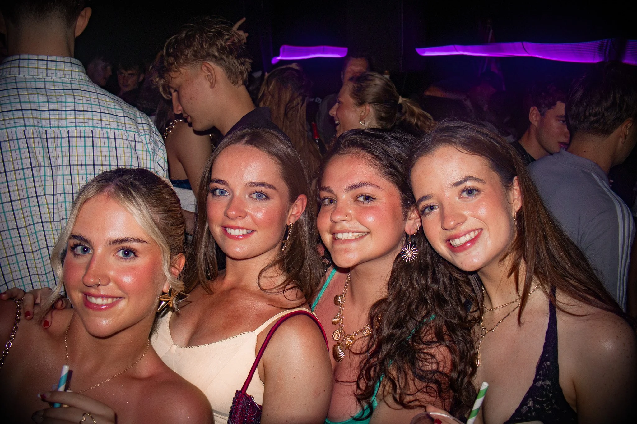 Four girls posing together at Split After Dark in Croatia, smiling in a packed club under purple neon lighting.