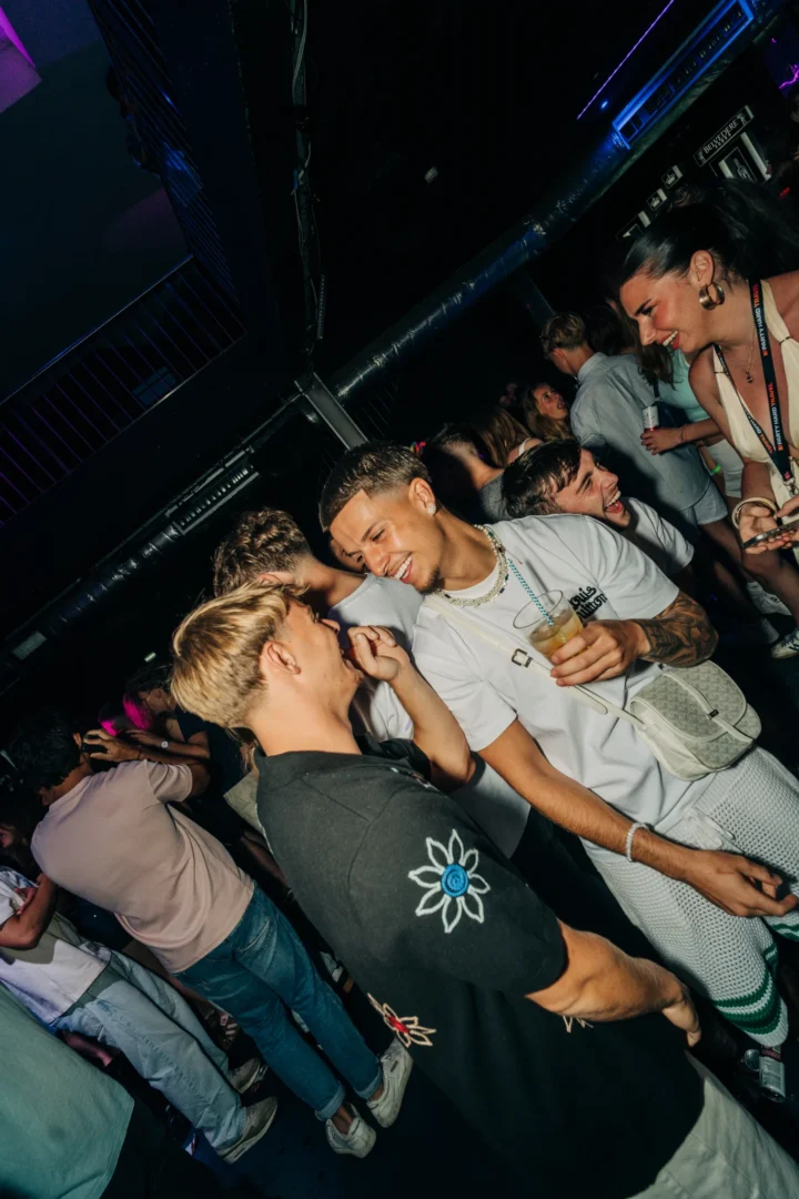 Lads chatting and laughing at the House of Tech event in Albufeira while the nightclub crowd socialises around them
