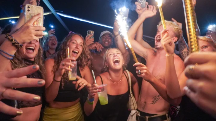 Crowd of girls and lads celebrating at Split After Dark in Croatia with sparklers, raised drinks and phones lighting up the dancefloor.
