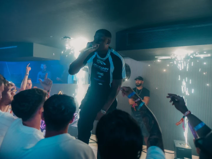 Napa Xtra Performer gripping the mic at Aqua Club in Ayia Napa while the front row points up and sparklers burst beside the stage